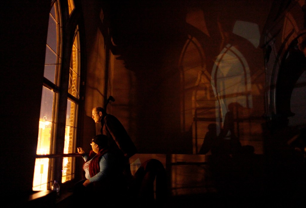 Jeff Jerome and Jeannette Marxen look out of a window in Westminster Hall overlooking Edgar Allan Poe's grave, waiting for the Poe Toast